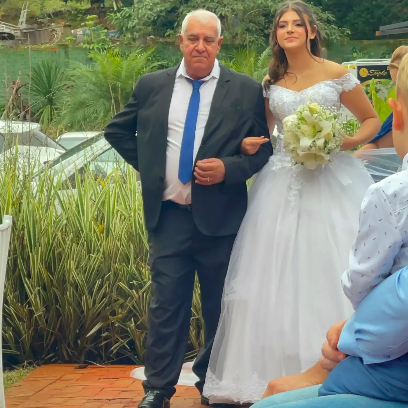 Noiva entrando com o pai pelo jardim, ao lado do lago